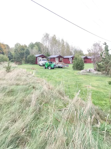 Lahtivõetud aia latid ja postid haagisel, kõrval roheline kompaktlaadur ja auto